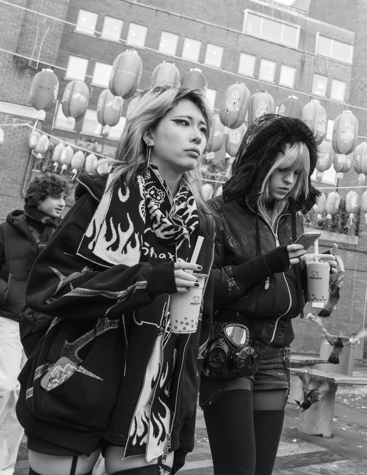 Two young women standing in London’s Chinatown, one carrying a distinctive gas-mask-shaped purse.