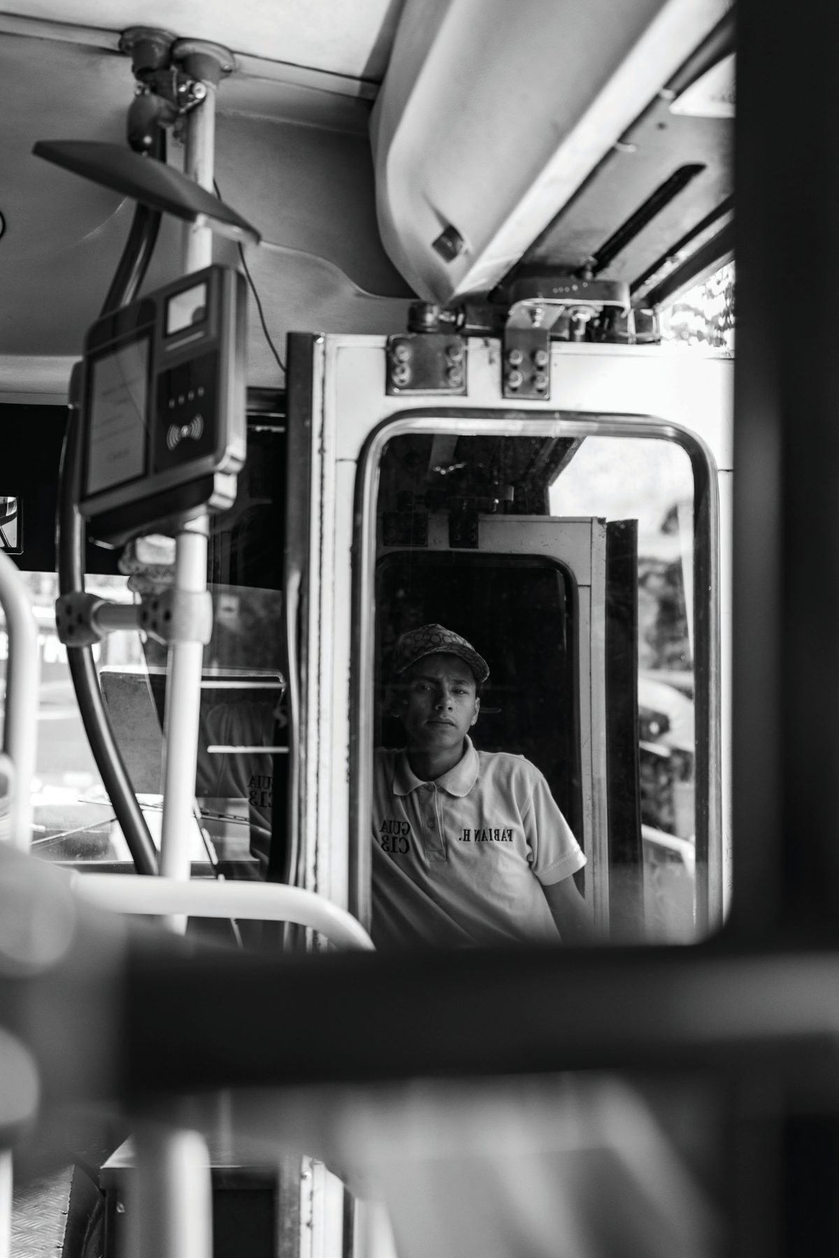A young guide seated near the front of a bus, reflected in its mirror and framed by the vehicle interior.