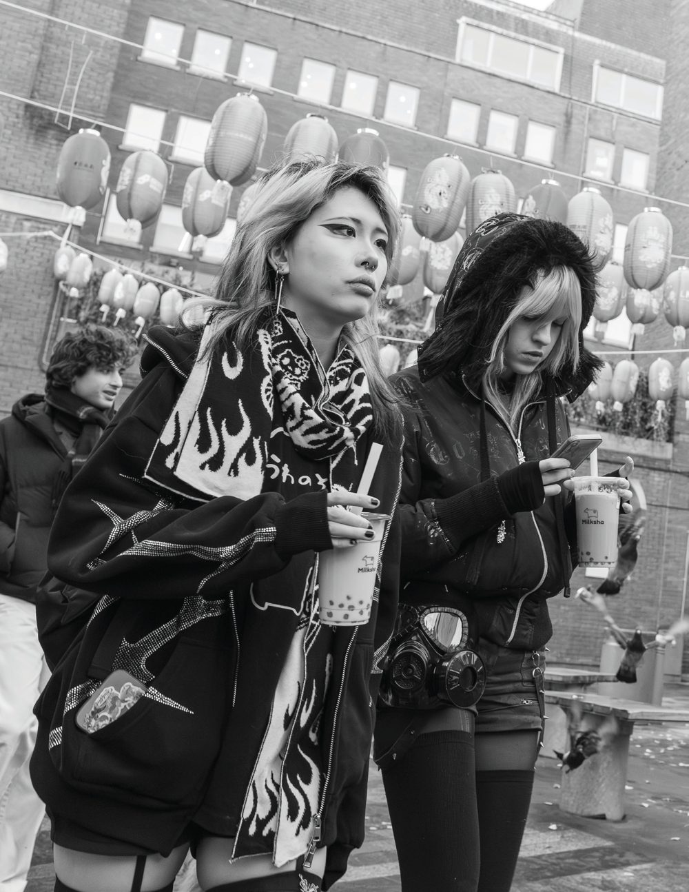 Two young women standing in London’s Chinatown, one carrying a distinctive gas-mask-shaped purse.