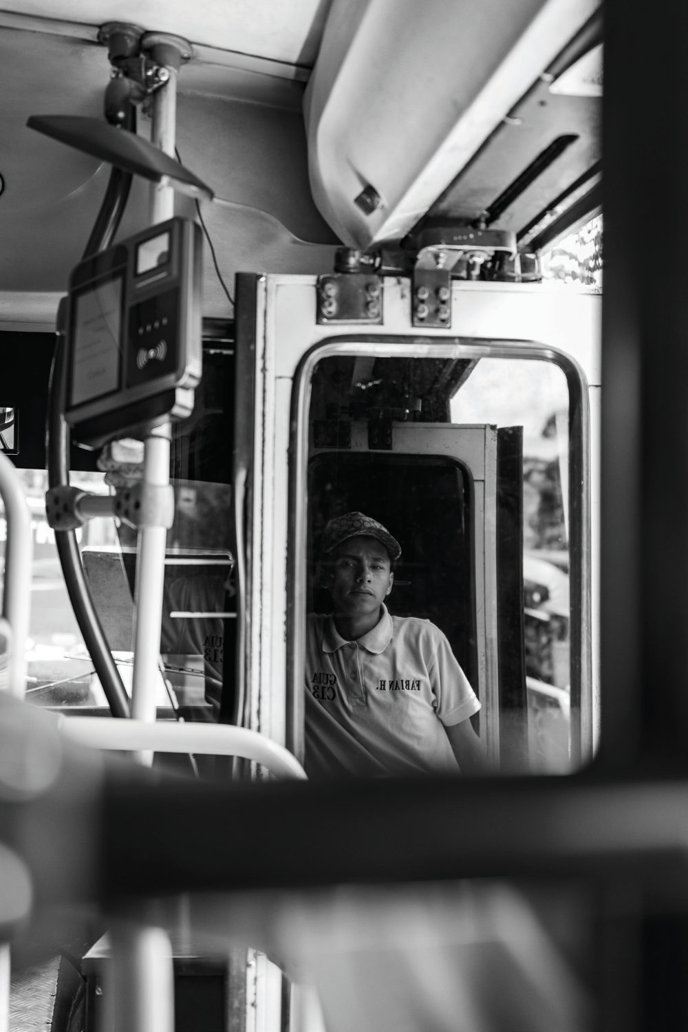 A young guide seated near the front of a bus, reflected in its mirror and framed by the vehicle interior.